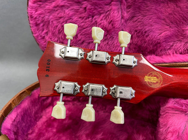 Back of vintage Gibson guitar headstock with six vintage tuners and serial number 9 3100 inside pink plush-lined guitar case