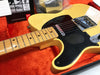 Close-up of vintage Fender Telecaster electric guitar with maple fretboard and black pickguard in orange plush-lined hard case with Fender owner's manual visible
