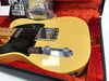 Vintage cream electric guitar with black pickguard and chrome hardware resting in red velvet-lined hard case