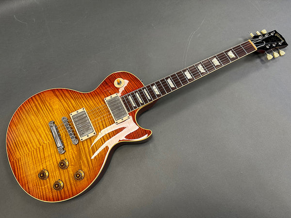 Electric guitar with sunburst flame maple top, dual humbucker pickups, and rosewood fretboard with trapezoid inlays, photographed on gray background