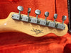 Close-up of Fender Custom Shop guitar headstock with vintage-style tuning pegs on orange plush case lining
