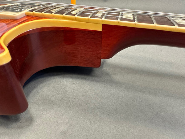 Close-up of vintage mahogany guitar neck joint with yellow binding and rosewood fretboard showing frets and strings, Coffee House Guitars product detail.