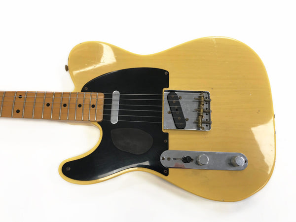 Vintage yellow electric guitar with black pickguard and maple fretboard, close-up on body and controls
