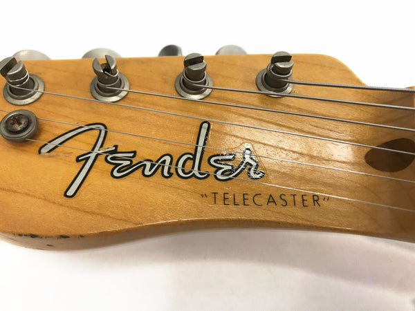 Close-up of Fender Telecaster guitar headstock with tuning pegs and strings on light wood finish