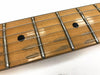 Close-up of maple guitar fretboard with dot inlays and frets, showing guitar strings and wood grain texture