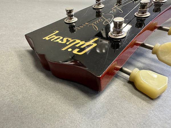 Close-up of Gibson guitar headstock with vintage tuners on gray background at Coffee House Guitars product listing