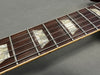 Close-up of rosewood guitar fretboard with pearl trapezoid inlays and metal frets on electric guitar neck