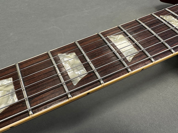 Close-up of rosewood guitar fretboard with pearl trapezoid inlays and metal frets on electric guitar neck