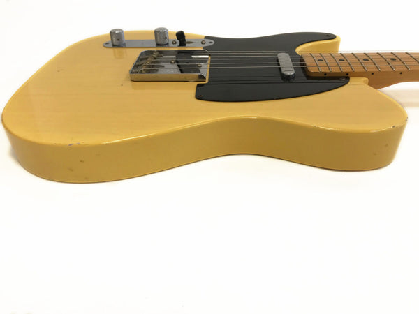 Vintage yellow electric guitar with black pickguard and chrome hardware on white background