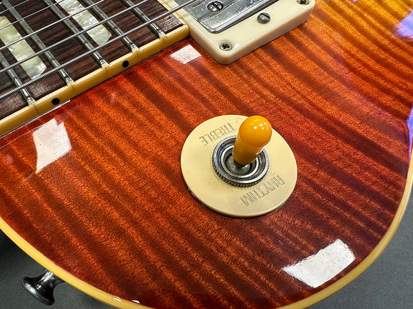 Close-up of cherry sunburst electric guitar body showing rhythm and treble switch, rosewood fretboard, and humbucker pickup.