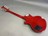 Back view of a cherry red electric guitar with a solid body and mahogany neck, featuring cream tuning pegs and black plastic control cavity covers.
