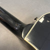 Close-up of black acoustic guitar neck and body joint showing strap button and cream binding details