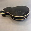 Black electric guitar back with cream binding and control cavity cover on gray background