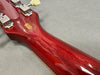 Close-up of glossy red guitar neck and headstock with vintage tuning pegs and historic collection emblem on back of headstock