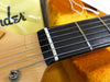 Close-up of Fender electric guitar headstock and nut with steel strings on orange plush guitar case background