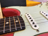 Close-up of electric guitar strings, pickups, and fretboard with dot inlays on a light-colored body with red accents at Coffee House Guitars.