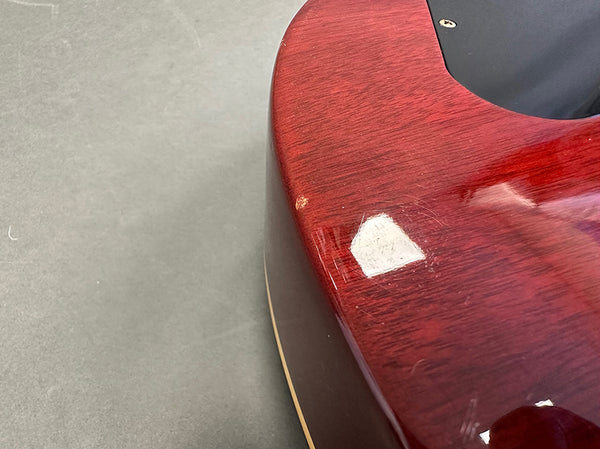 Close-up of red electric guitar body showing scratch and paint chip damage on glossy finish at Coffee House Guitars.