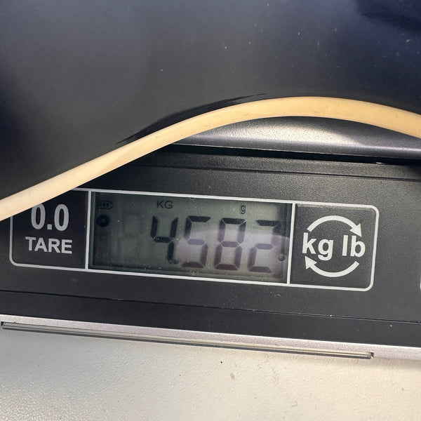 Close-up of digital scale showing guitar weight of 4.582 kilograms with part of guitar body visible on the scale.