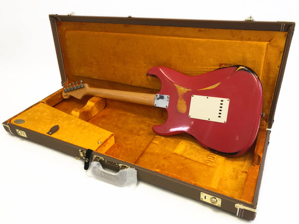 Vintage red electric guitar with worn finish in open brown hard case with orange interior lining