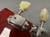 Close-up of vintage Kluson Deluxe guitar tuning pegs with cream plastic buttons on red guitar headstock