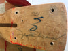 Close-up of a guitar neck heel with natural wood grain, signature, handwritten numbers, and red paint marks, featuring drilled holes for mounting.