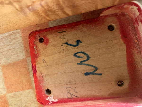 Close-up image of guitar neck pocket with handwritten numbers inside a red-finished electric guitar body cavity