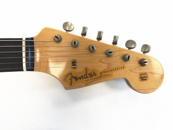 Close-up of Fender Stratocaster guitar headstock with tuning pegs and logo on natural wood finish