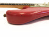 Close-up of red electric guitar body showing worn finish and scratches, partial view of maple neck and fretboard on white background