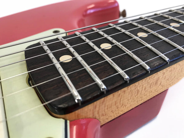 Close-up of guitar neck showing dark wood fretboard with metal frets and dot inlays on red-bodied electric guitar