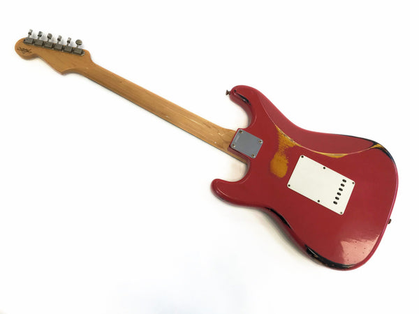 Rear view of vintage red electric guitar with natural wood neck and visible wear and tear on body, showing back plate and metal neck plate on white background