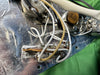Close-up of vintage electric guitar wiring and potentiometers showing white and yellow wires soldered to metal control plate with green fabric background