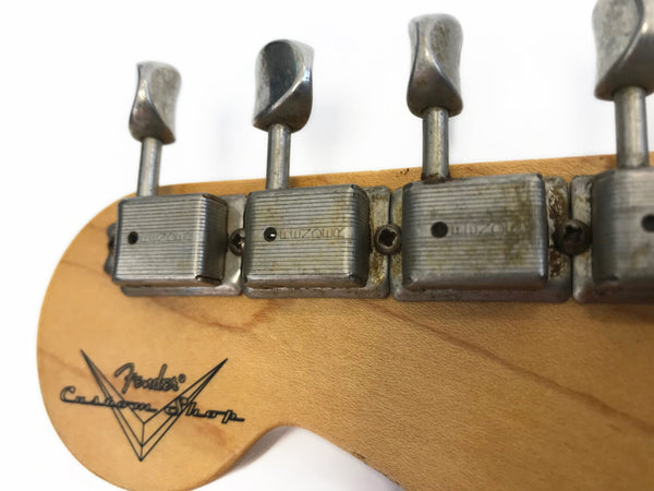 Close-up of vintage Fender Custom Shop guitar headstock showing aged tuning machines and logo on natural wood finish