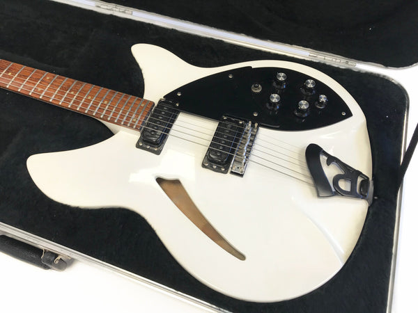 White semi-hollow electric guitar with black pickguard and dual humbucker pickups in hard case with black plush lining