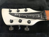 Close-up of white Rickenbacker electric guitar headstock with six tuning pegs and metal Rickenbacker logo plate, made in the USA, on a black background