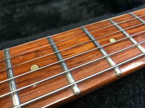 Close-up of guitar fretboard with metal frets and steel strings on polished wood background from Coffee House Guitars
