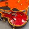 Red semi-hollow electric guitar with dual humbucker pickups inside vintage orange velvet-lined guitar case