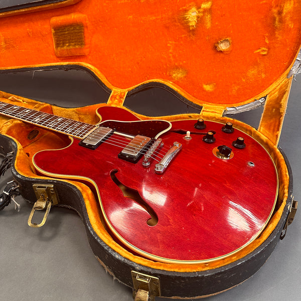 Red semi-hollow electric guitar with dual humbucker pickups inside vintage orange velvet-lined guitar case