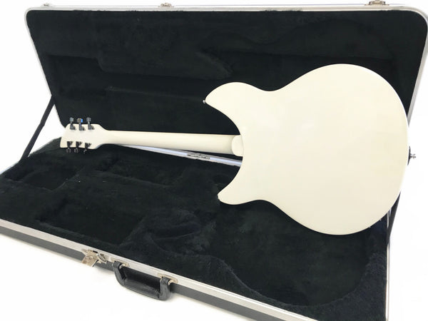 White electric guitar shown from the back inside a black plush-lined hard case with silver latches and handle, on a white background.