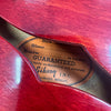 Close-up of Gibson guitar label inside a red semi-hollow body guitar showing vintage guarantee and Kalamazoo, Michigan text