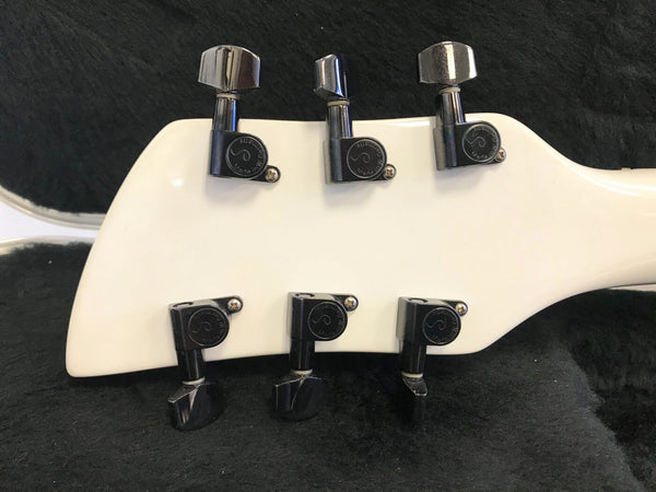 Close-up of white guitar headstock with six black Grover tuning pegs against black guitar case interior