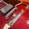 Close-up of vintage red electric guitar bridge, tailpiece, and pickup with metal hardware and six strings