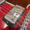 Close-up of vintage chrome electric guitar pickup and strings on red sunburst guitar body with adjustable bridge saddles