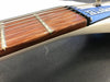 Close-up of electric guitar neck and strings showing rosewood fretboard and white guitar body on black textured surface