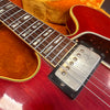 Close-up of red electric guitar body and neck showing metal pickup, rosewood fretboard with mother-of-pearl trapezoid inlays, and vintage strings on orange guitar case interior