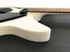 Close-up of white electric guitar body with black pickups and brown fretboard on black surface at Coffee House Guitars