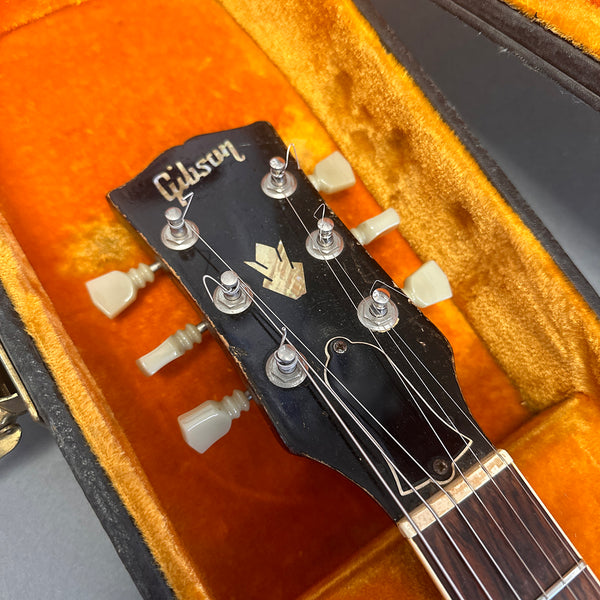 Close-up of Gibson guitar headstock with vintage tuners inside orange plush guitar case