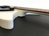 Close-up side view of white electric guitar body and rosewood fretboard on black surface for Coffee House Guitars product listing