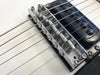 Close-up image of electric guitar bridge and strings with black pickup on white guitar body