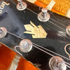 Close-up of vintage guitar headstock with pearl arrow inlay and tuning pegs on black finish guitar neck