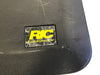 Close-up of vintage Rickenbacker black guitar case logo plate with yellow RIC lettering and textured surface